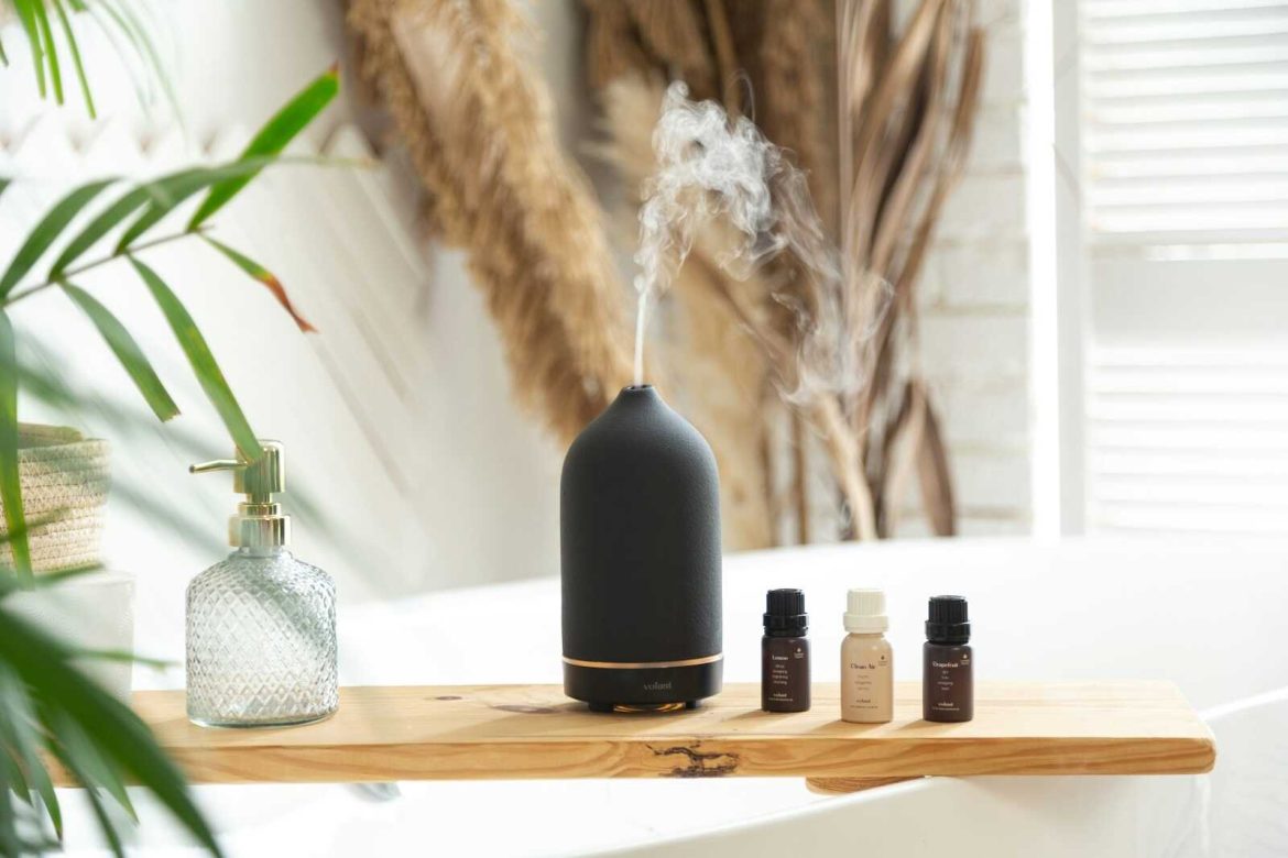Yoga aromatherapy diffuser with essential oils releasing calming mist in a peaceful home yoga space.